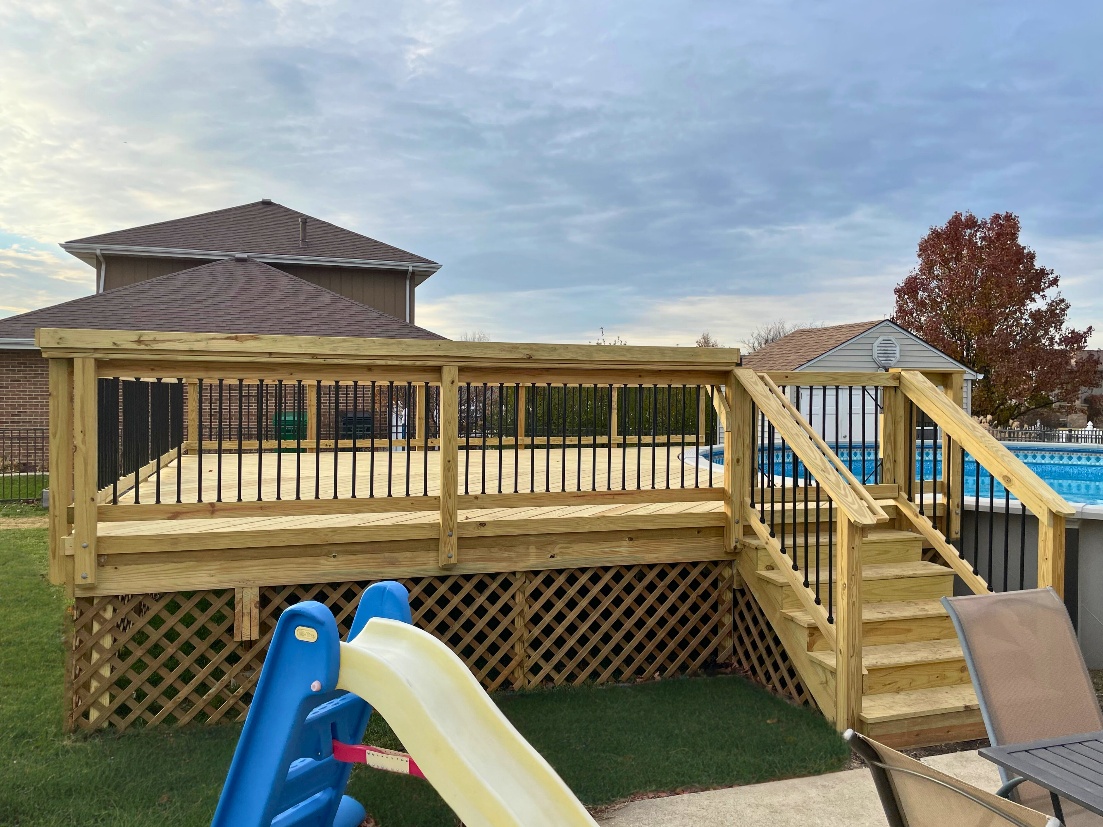 Newly constructed wooden deck with black metal balusters, stairs, and a child's slide next to an above-ground swimming pool in Homer Glen.